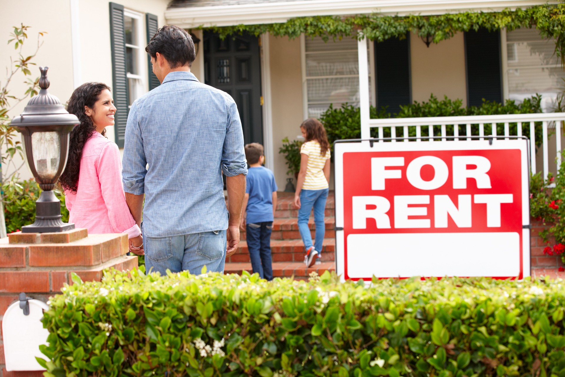Smiling Hispanic family outside rental home