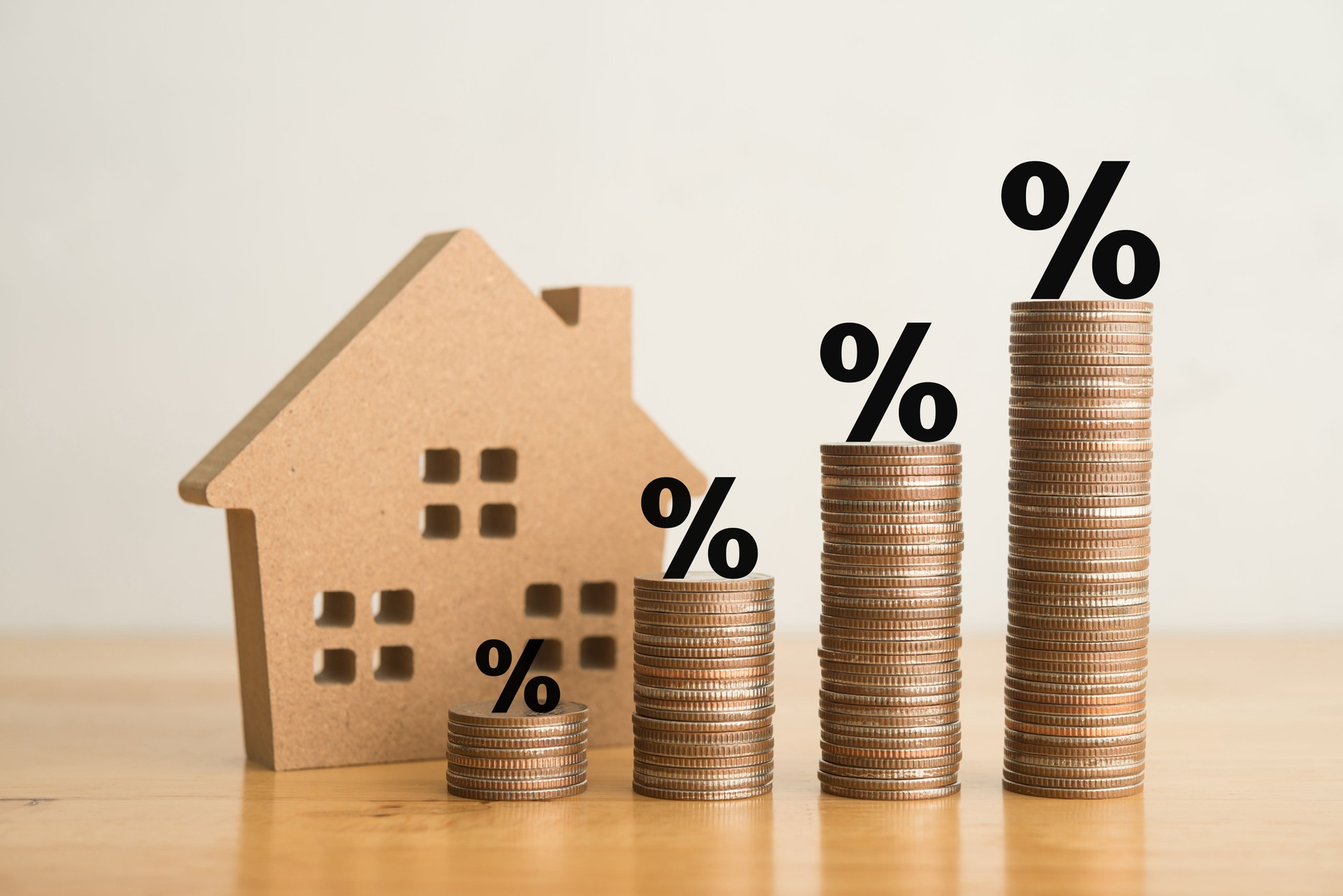 Stack coins as graph trend up and interest rates with house model background.
